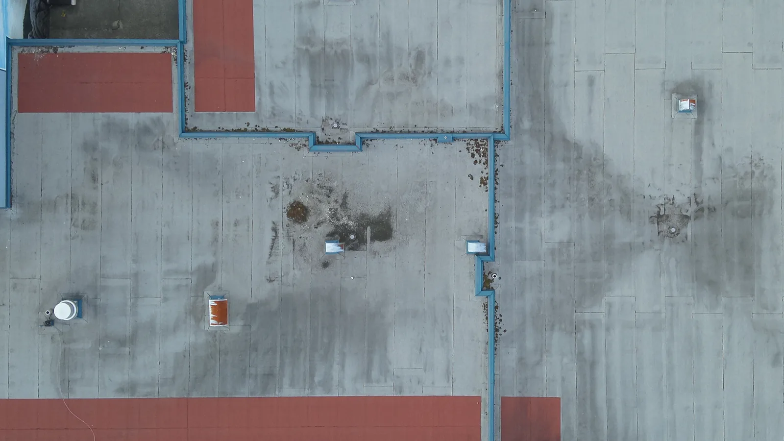 RGB close-up of a low-slope roof membrane from the DJI Matrice 30T wide camera, showing parapet junctions, a roof hatch and two vents.